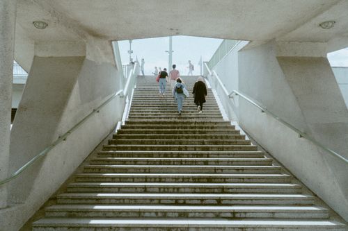 Free Commuters on a sunlit urban staircase in a cityscape setting. Stock Photo