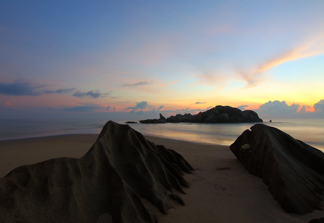 бесплатная Остров на море под голубым небом в золотой час Стоковое фото