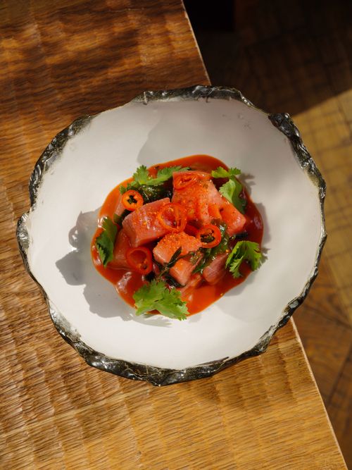 Free Top view of a salmon dish garnished with fresh herbs and red chili in a decorative bowl. Stock Photo