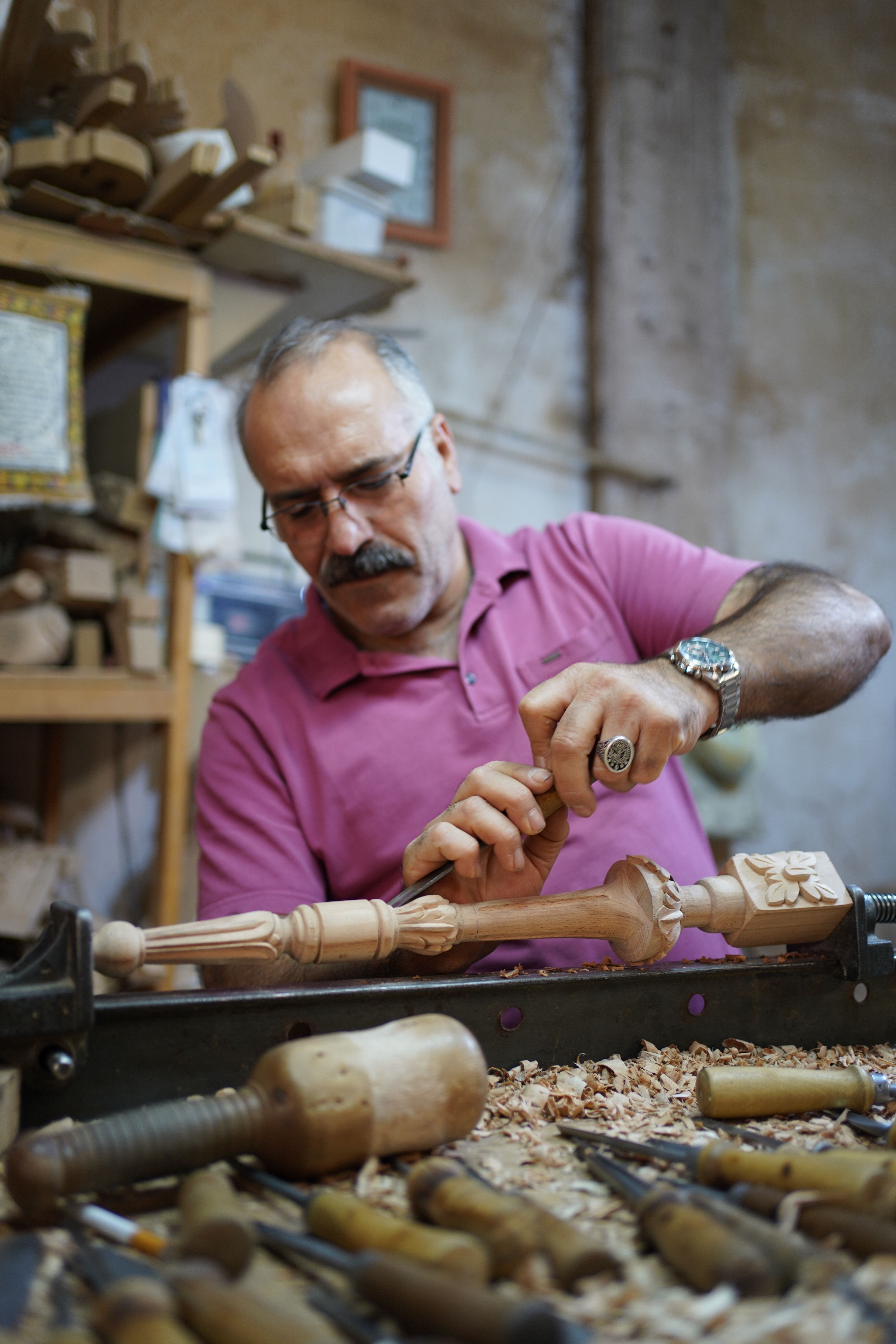 Elderly craftsman focused on intricate woodwork in a traditional workshop.
