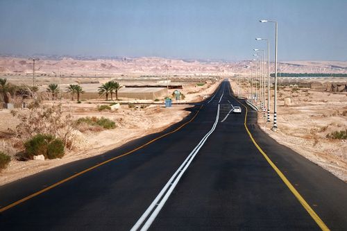 Free A long road stretches through a barren desert, under a clear blue sky, offering a sense of isolation and adventure. Stock Photo