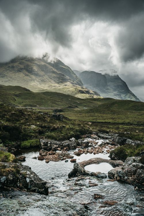 Free Scenic view of Glencoe, Scotland with dramatic overcast skies and mountain stream. Stock Photo
