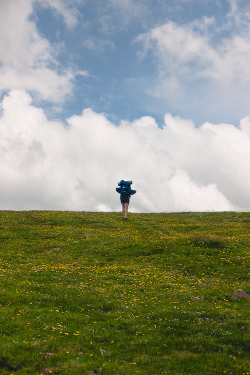 A Person Hiking on a Grass Hill 