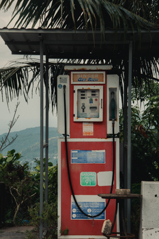 Old gas pump at a vintage gas station in Bangkok, surrounded by tropical foliage.