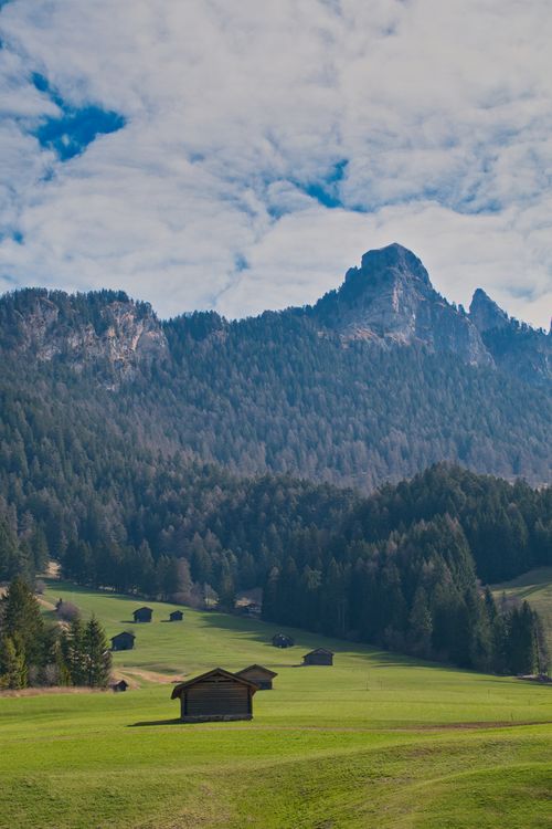 Free A picturesque view of mountains and green fields, capturing nature's tranquility and beauty. Stock Photo
