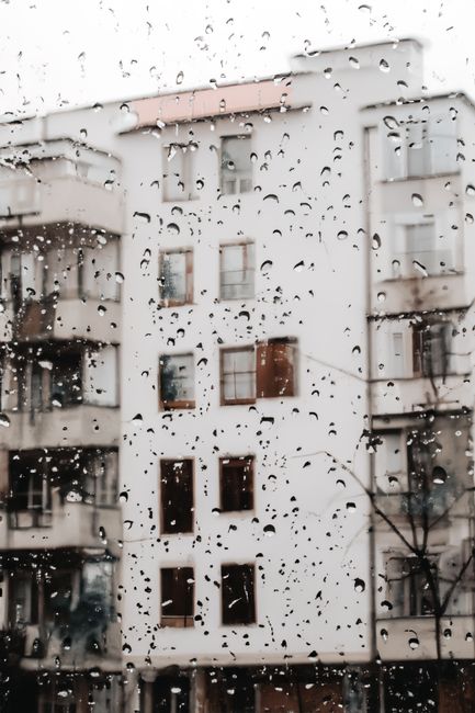 Urban apartment buildings seen through raindrop-covered glass, capturing a rainy day mood.