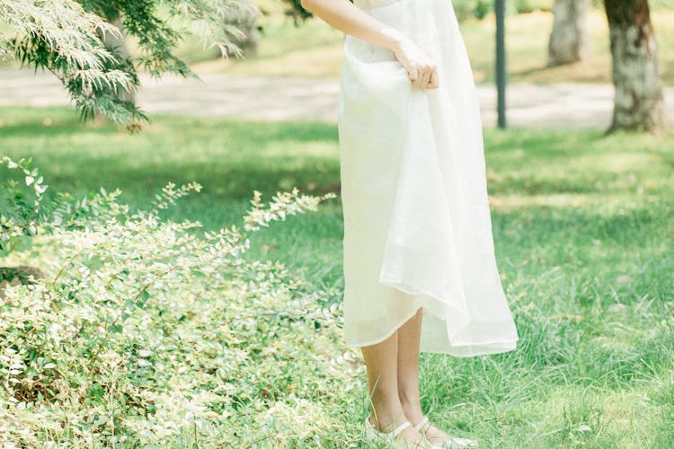 Woman Standing In White Sundress On Grass