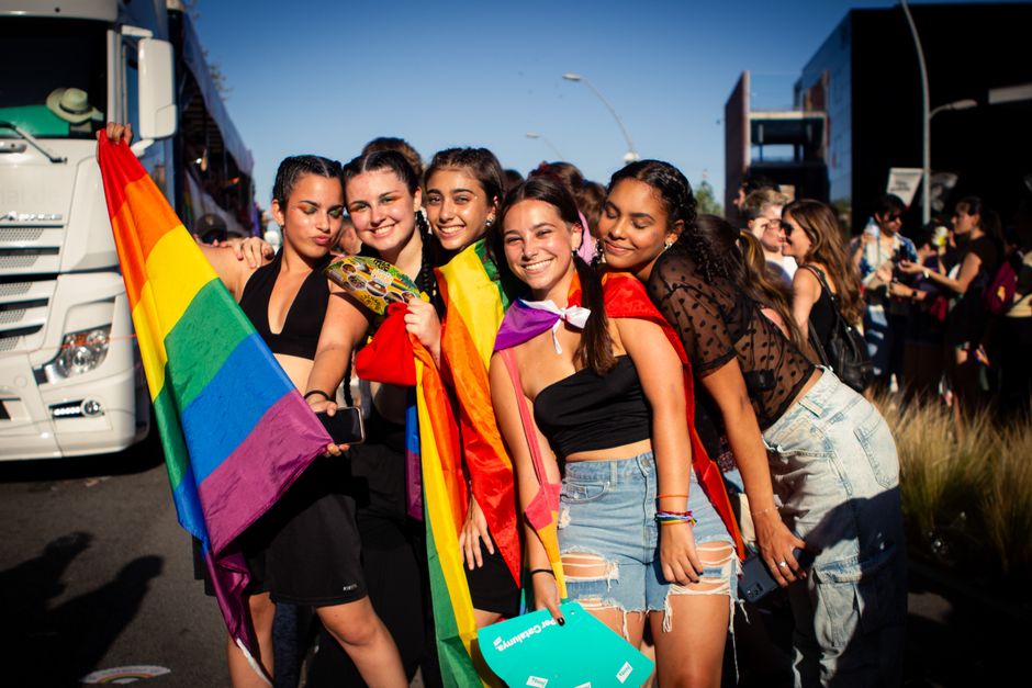 Un grupo alegre de jóvenes celebrando en el vibrante Festival del Orgullo de Barcelona con banderas arcoíris.