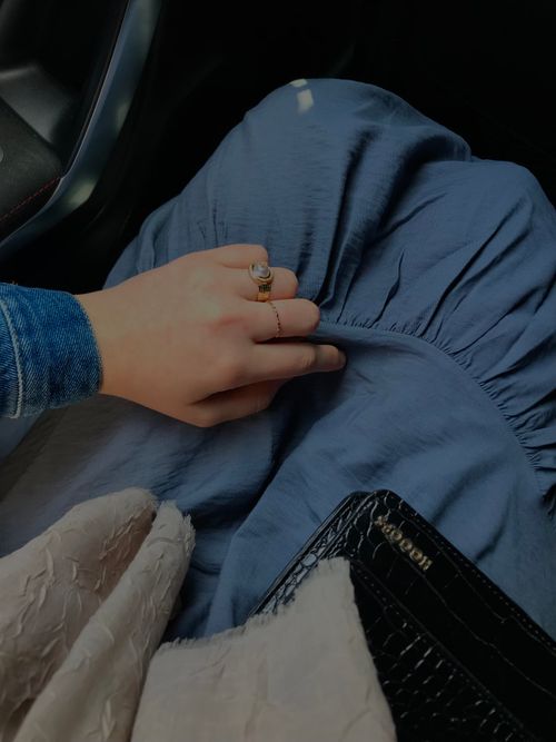 Free Elegant hand adorned with rings resting on a blue dress with a purse in view. Stock Photo