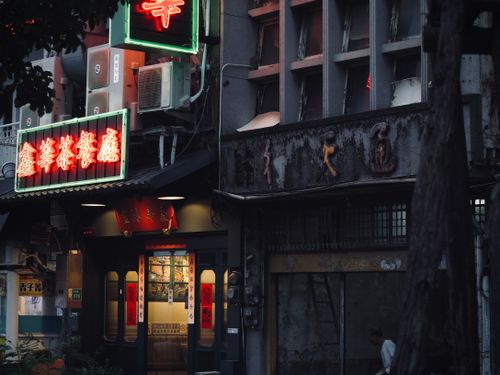 Free A dimly lit Chinese restaurant facade with neon signs in an urban setting during dusk. Stock Photo