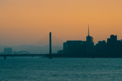 Free Silhouette of a city skyline and bridge at sunset, creating a dramatic urban view. Stock Photo