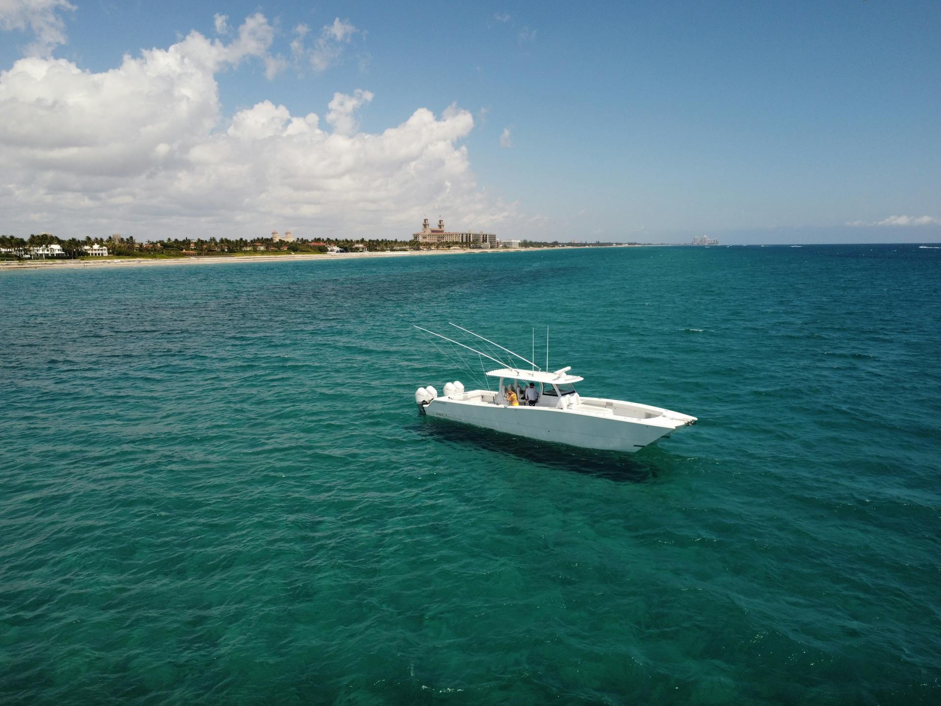 A motorboat cruising on clear blue waters near Palm Beach, Florida coastline under a sunny sky.