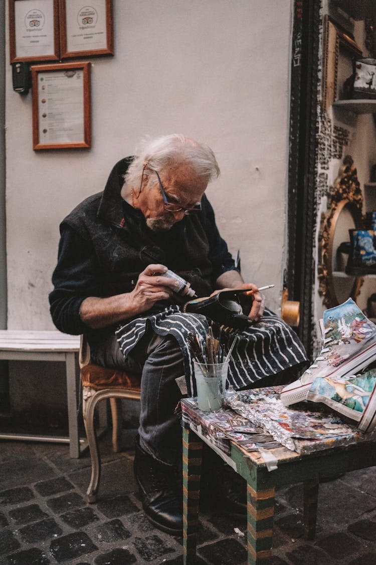 Elderly Man Sitting And Fixing Shoes