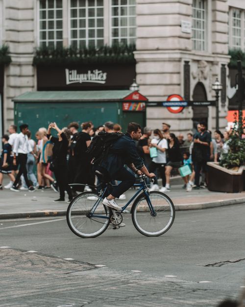 Free A man on a bicycle rides through a crowded street in London, UK, showcasing urban life. Stock Photo