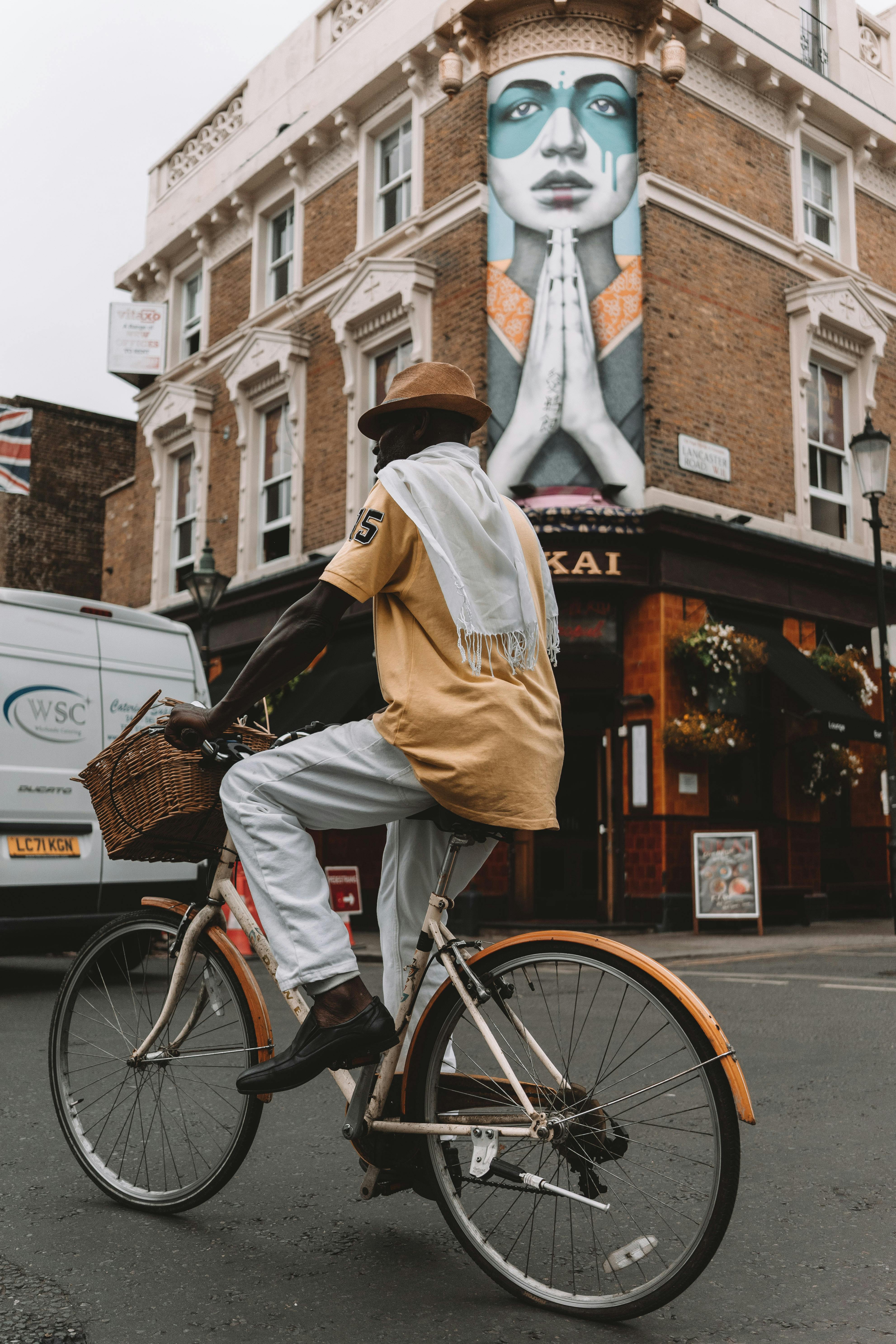 A cyclist rides past a vibrant mural on a street in London, capturing urban life and culture.