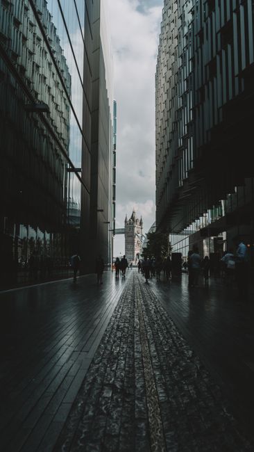 View of Tower Bridge framed by modern urban architecture, featuring pedestrians.