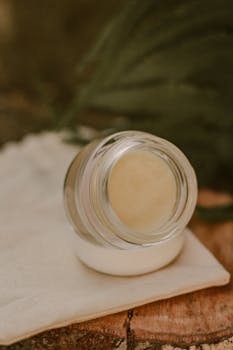 Glass jar of cream displayed on a rustic surface, ideal for natural skincare themes.