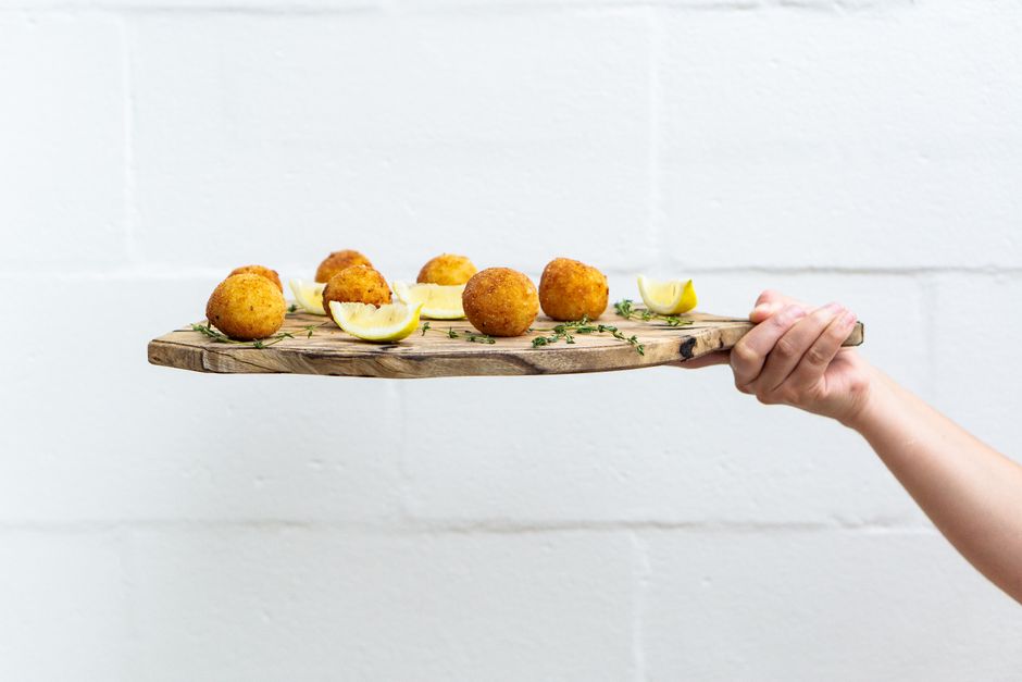 Tasty arancini balls served with lemon slices on a rustic wooden board, perfect for a fresh and healthy meal.