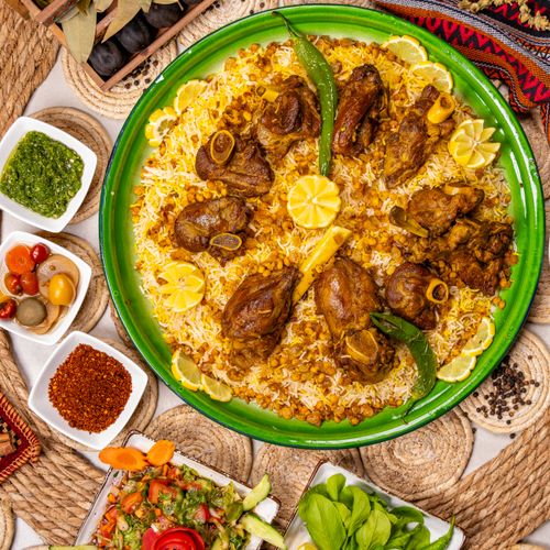 Free Top view of a flavorful lamb rice dish with spices, herbs, and lemon garnishes. Stock Photo