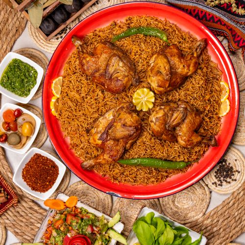 Free A vibrant platter of grilled chicken and spiced rice with assorted side dishes. Stock Photo