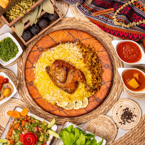 Free A flavorful Middle Eastern meal featuring roasted chicken on rice with assorted sides and sauces. Stock Photo