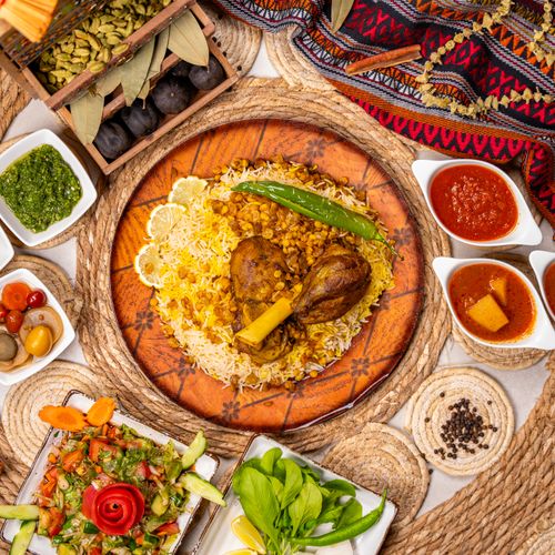 Free A beautifully arranged Middle Eastern kabsa dish surrounded by various colorful sauces and fresh vegetables. Stock Photo