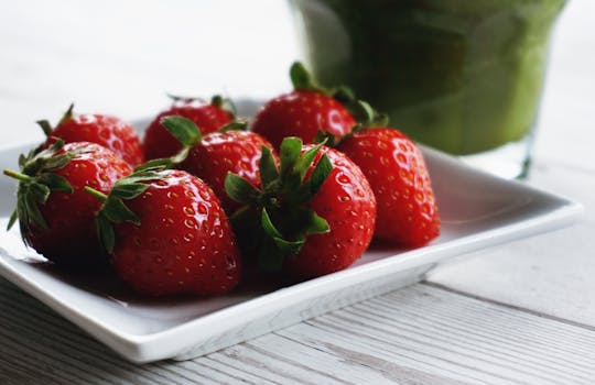 Close-up of fresh ripe strawberries on a white plate, vibrant and delicious.
