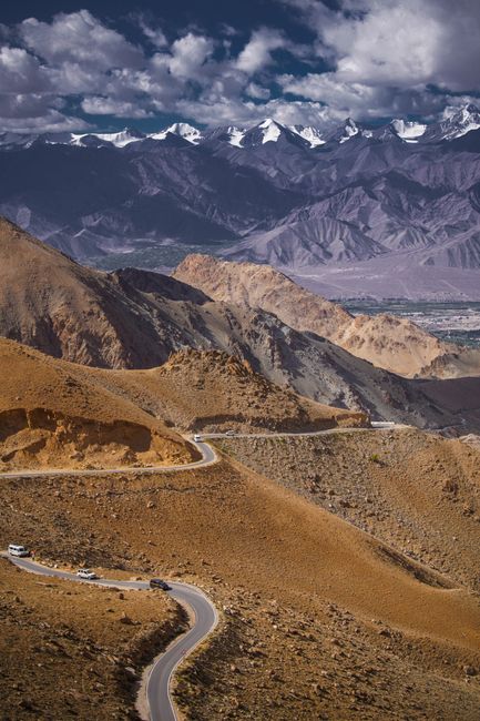 Winding road through majestic mountains in Ladakh, India, under a clear sky.