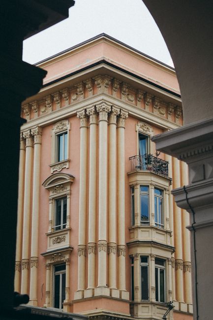 Elegant neoclassical townhouse with ornate columns and facade, captured from a low angle shot.