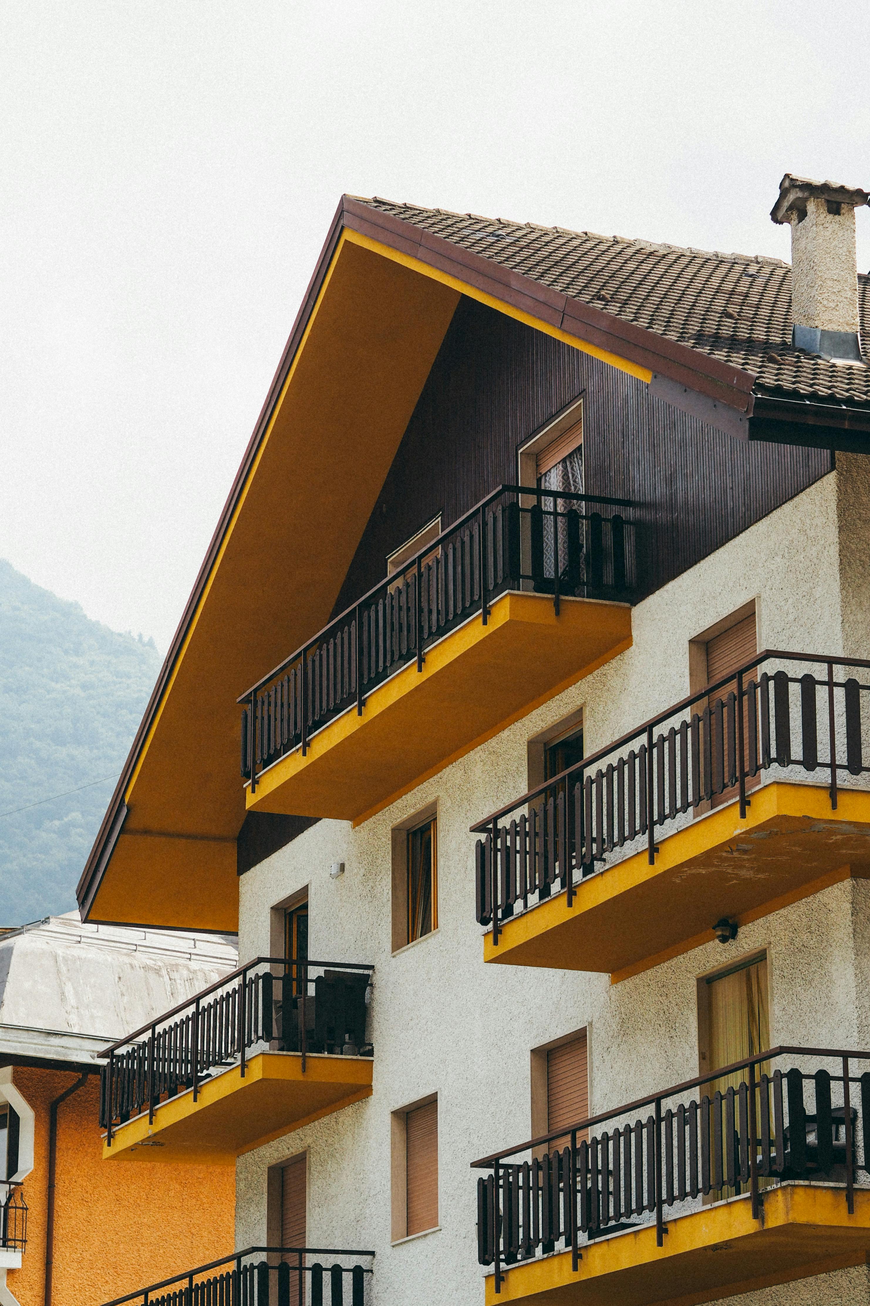 Charming alpine-style house with distinct yellow balconies nestled in a village setting.