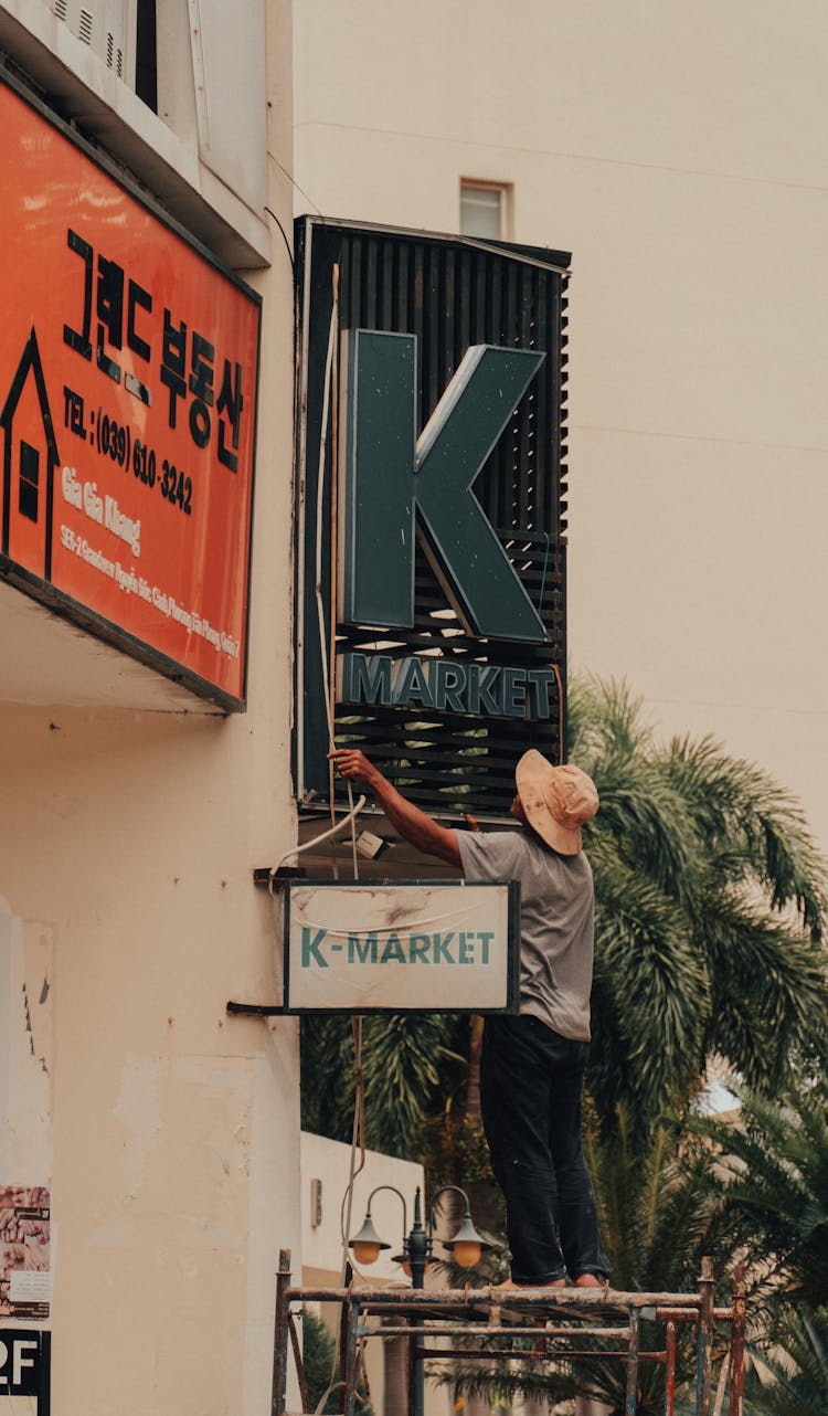 Man Standing On Scaffolding By Commercial Sign