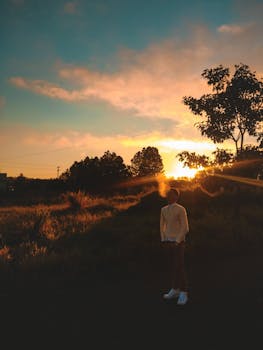 夕阳西下，一个人物沉思地站在大自然中，勾勒出美丽的轮廓