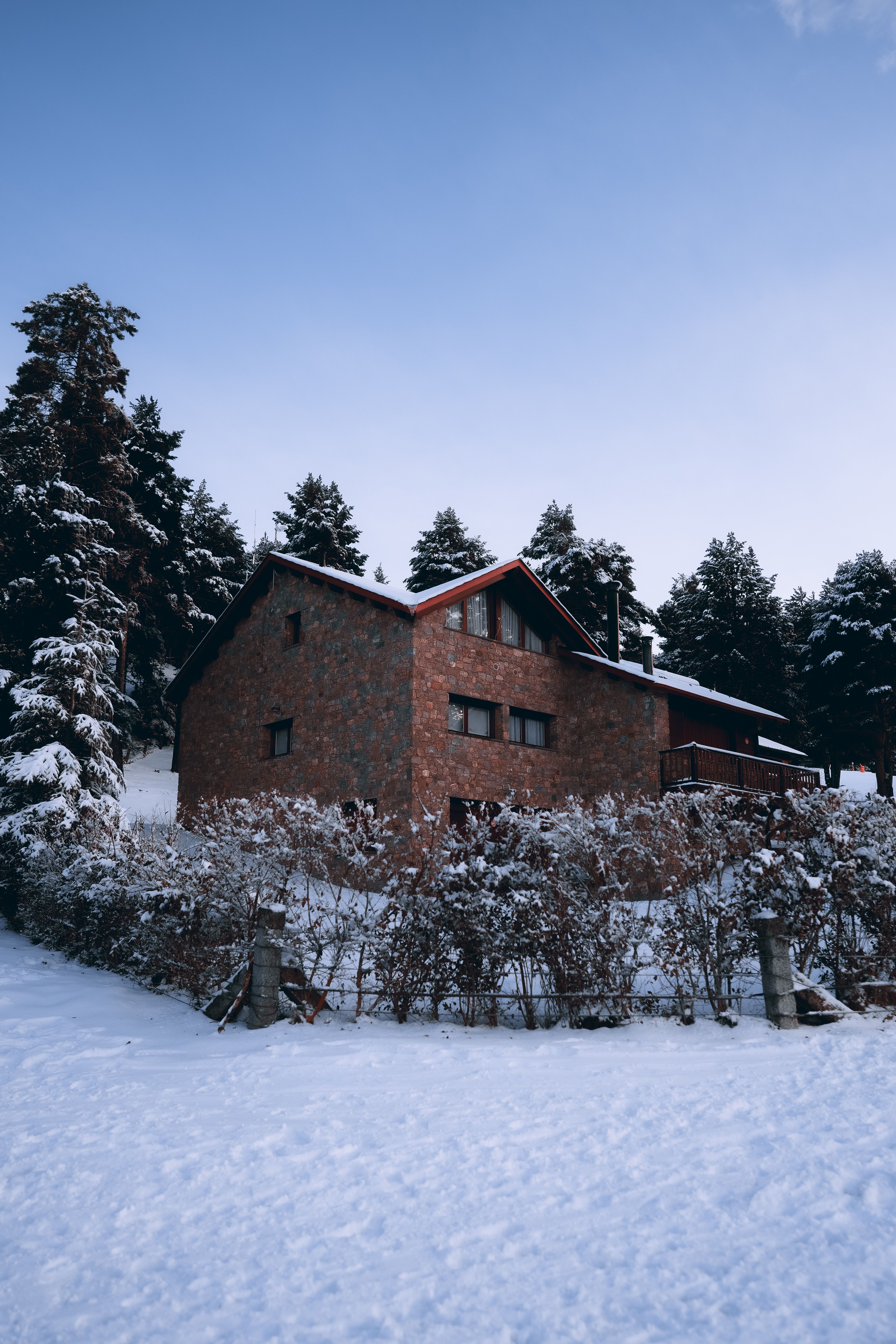 Charming brick house in a snowy forested landscape in La Molina, Spain during winter.