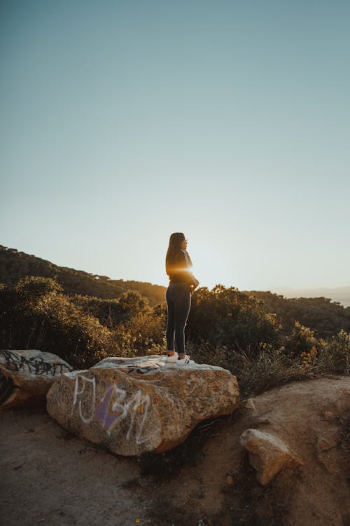 Woman Standing on Rock under Clear Sky