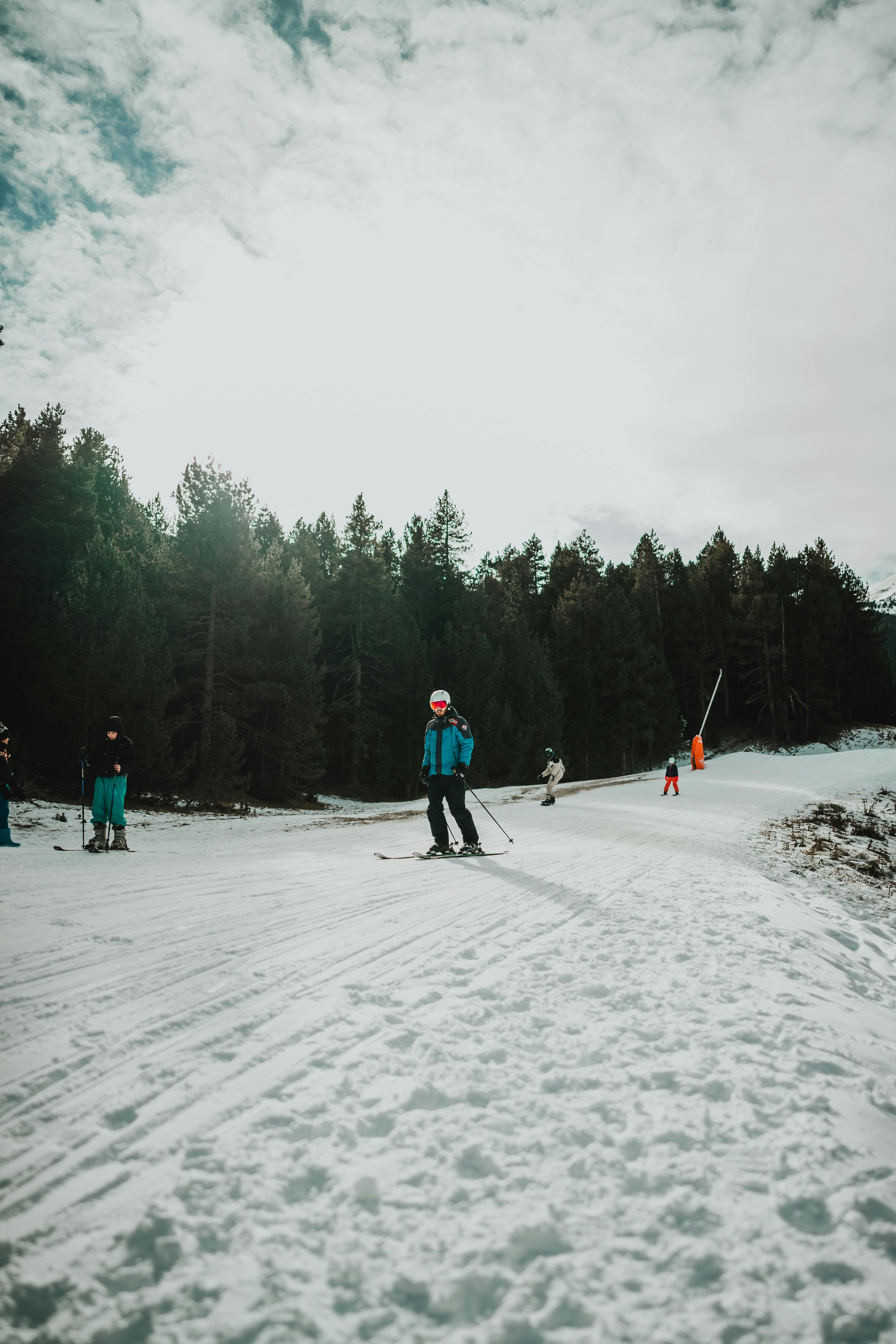 Skiers enjoying a winter day on a snowy slope in a forested area in Spain.