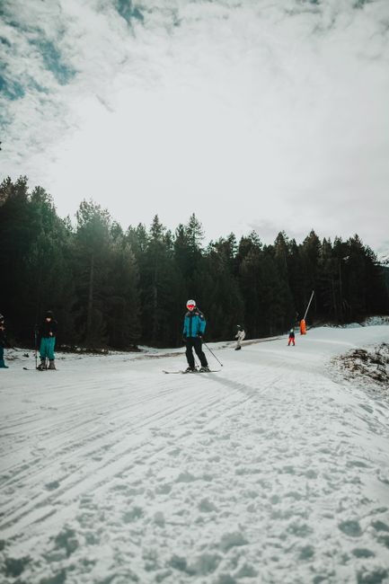 Skiers enjoying a winter day on a snowy slope in a forested area in Spain.