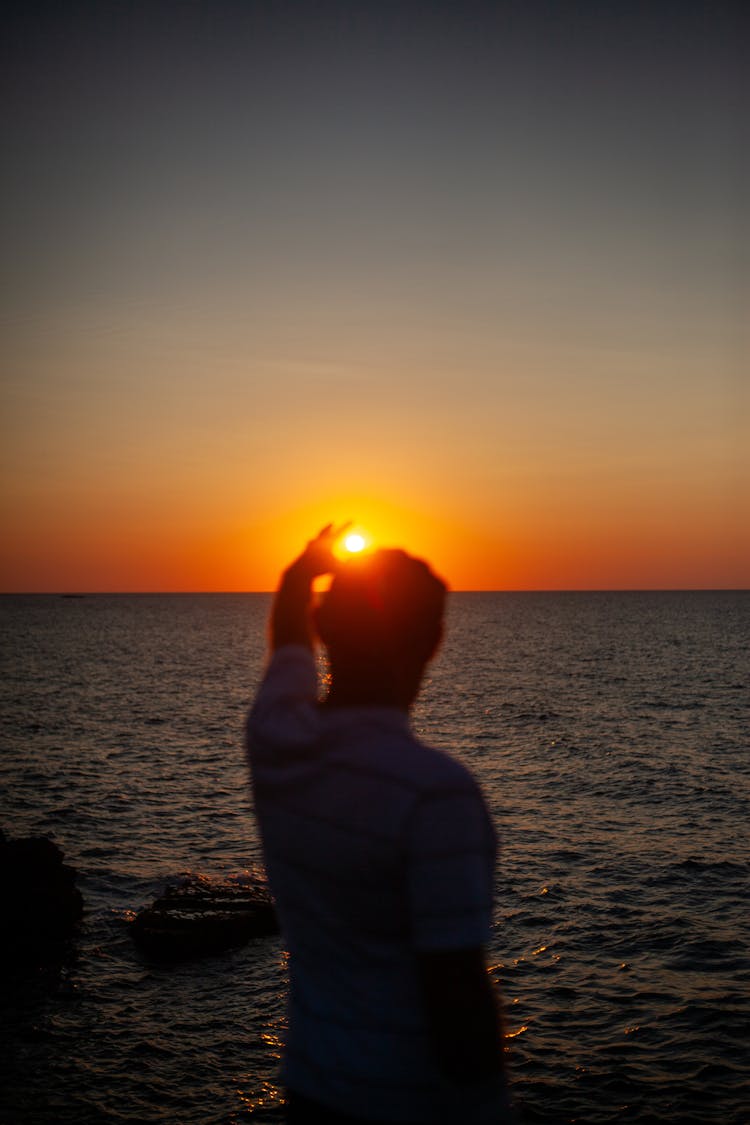 Man Catching Sun At Sunset On Sea Shore 