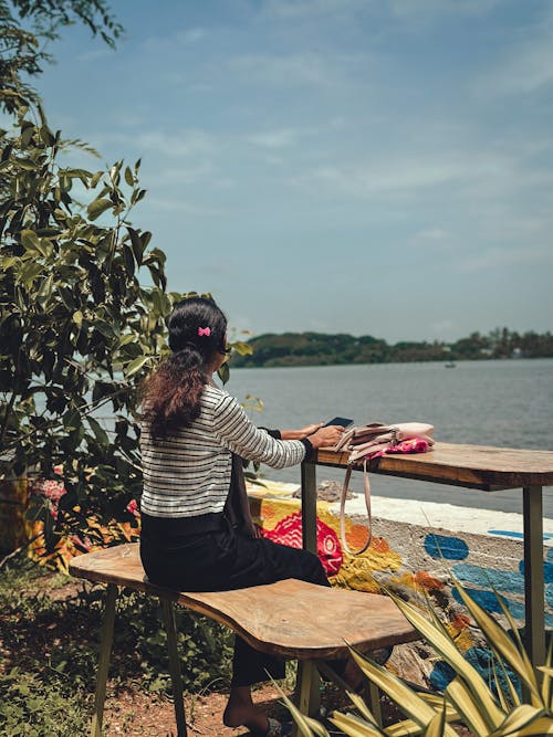 Woman Sitting by Table near Water