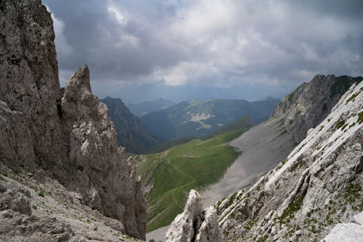 Stunning view of a rocky mountain landscape with green valleys under cloudy skies.