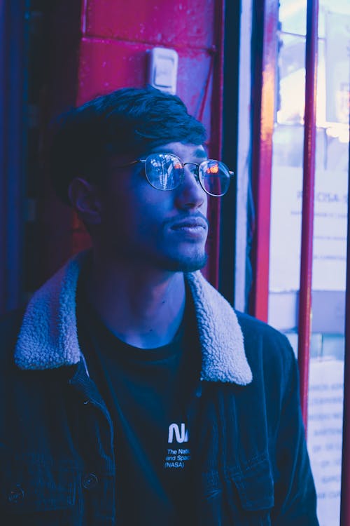 Young Man with Eyeglasses Standing by Wall