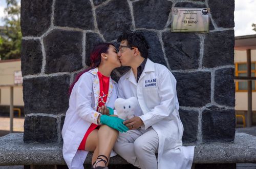Free A young couple wearing lab coats shares a romantic moment by a stone monument outdoors. Stock Photo
