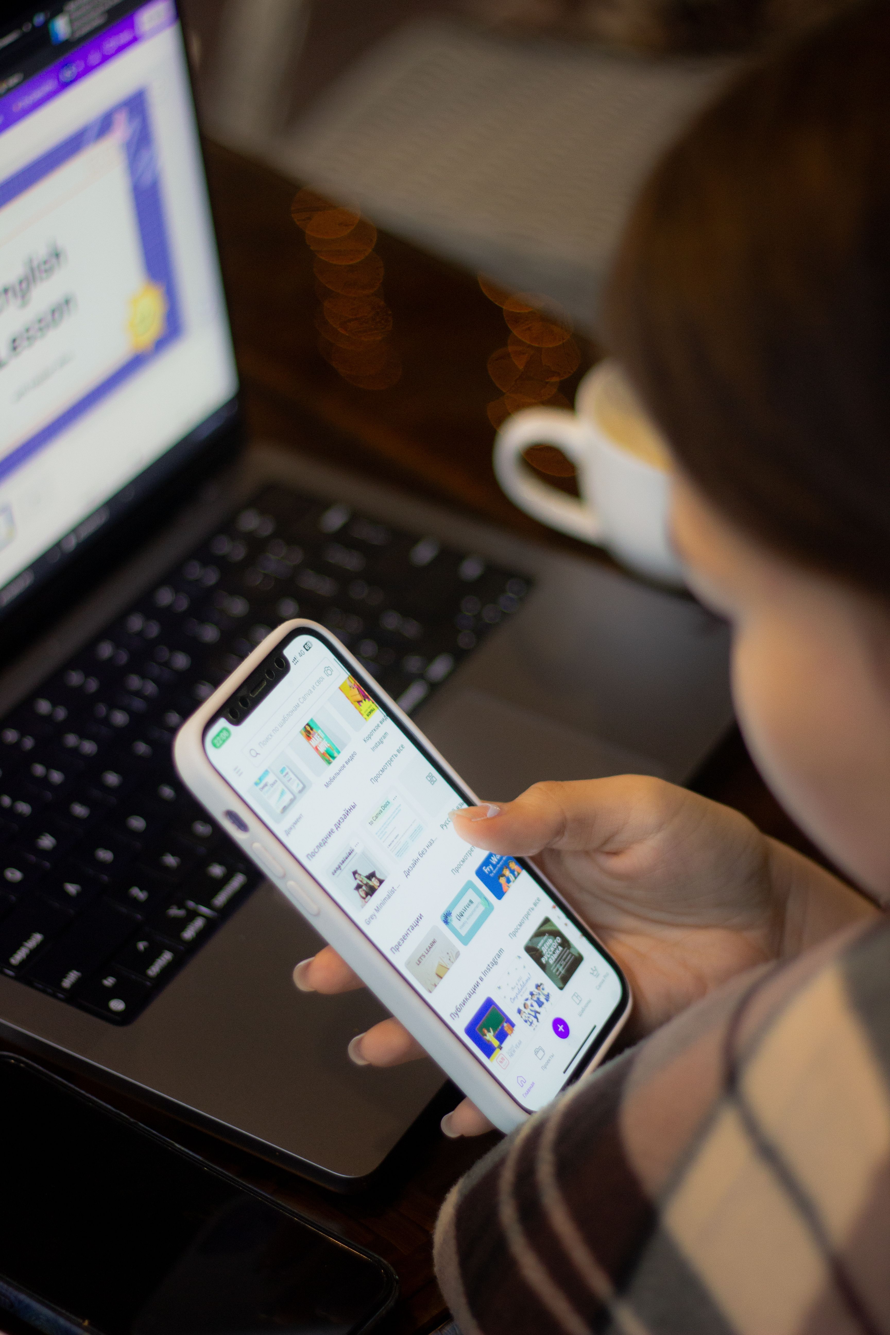 Adult woman using smartphone and laptop indoors, focused on device.