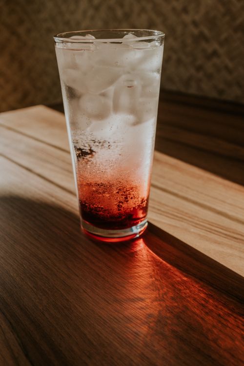 Free Chilled beverage in a tall glass with a striking red gradient on a wooden table. Stock Photo