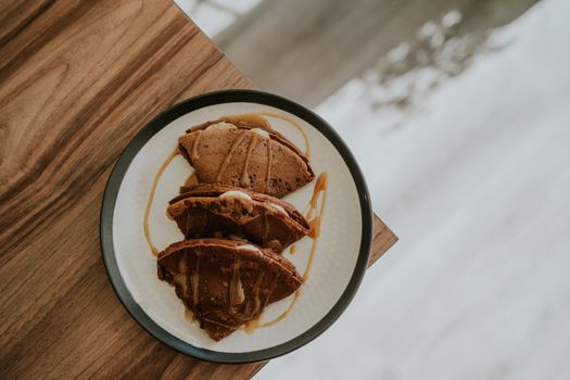 A top view of chocolate pancakes on a plate drizzled with syrup, perfect for sweet lovers.