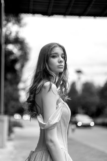 Stylish black and white portrait of a young woman in an outdoor urban setting.