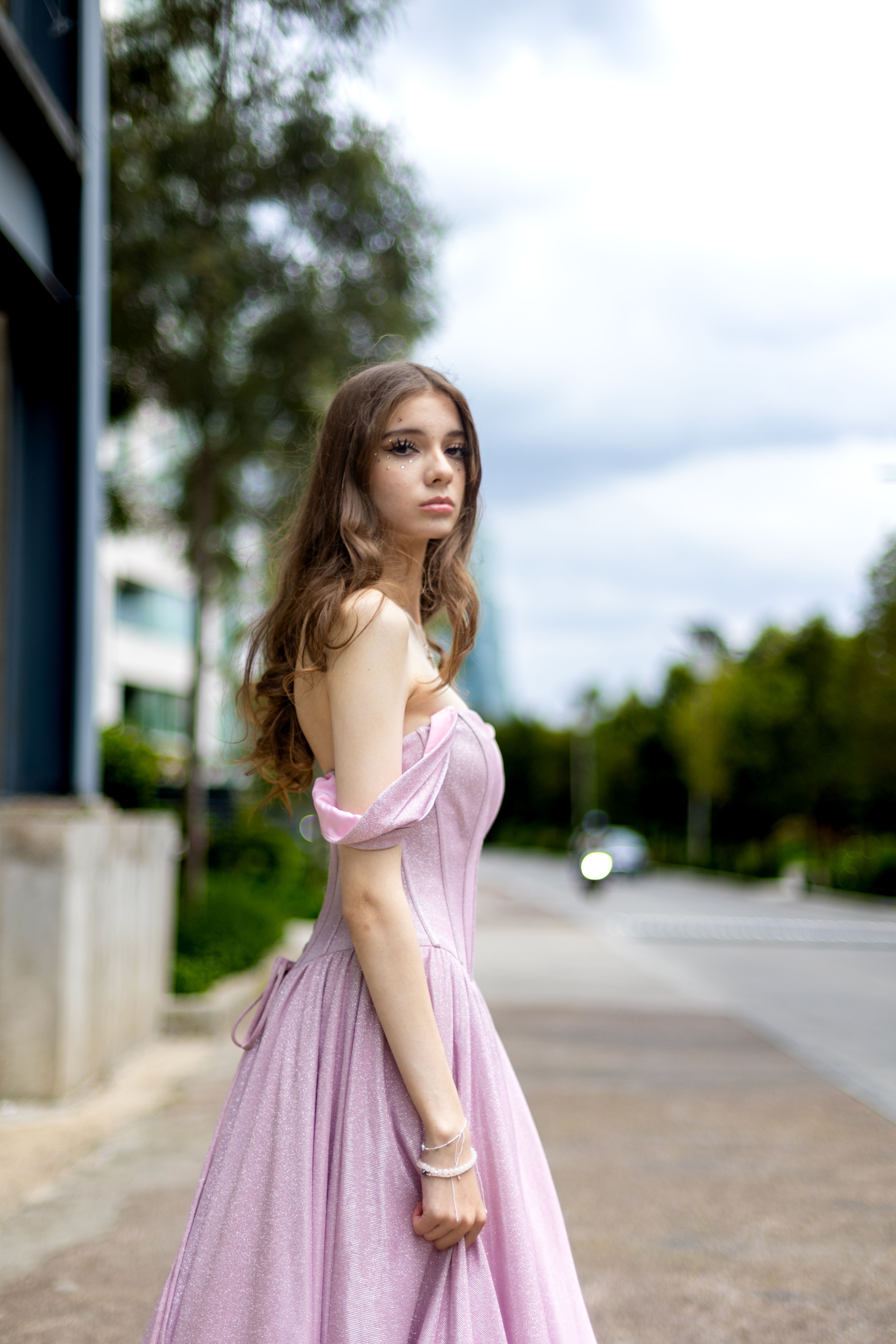 A woman in a pink dress is standing on a street  Free Stock Photo