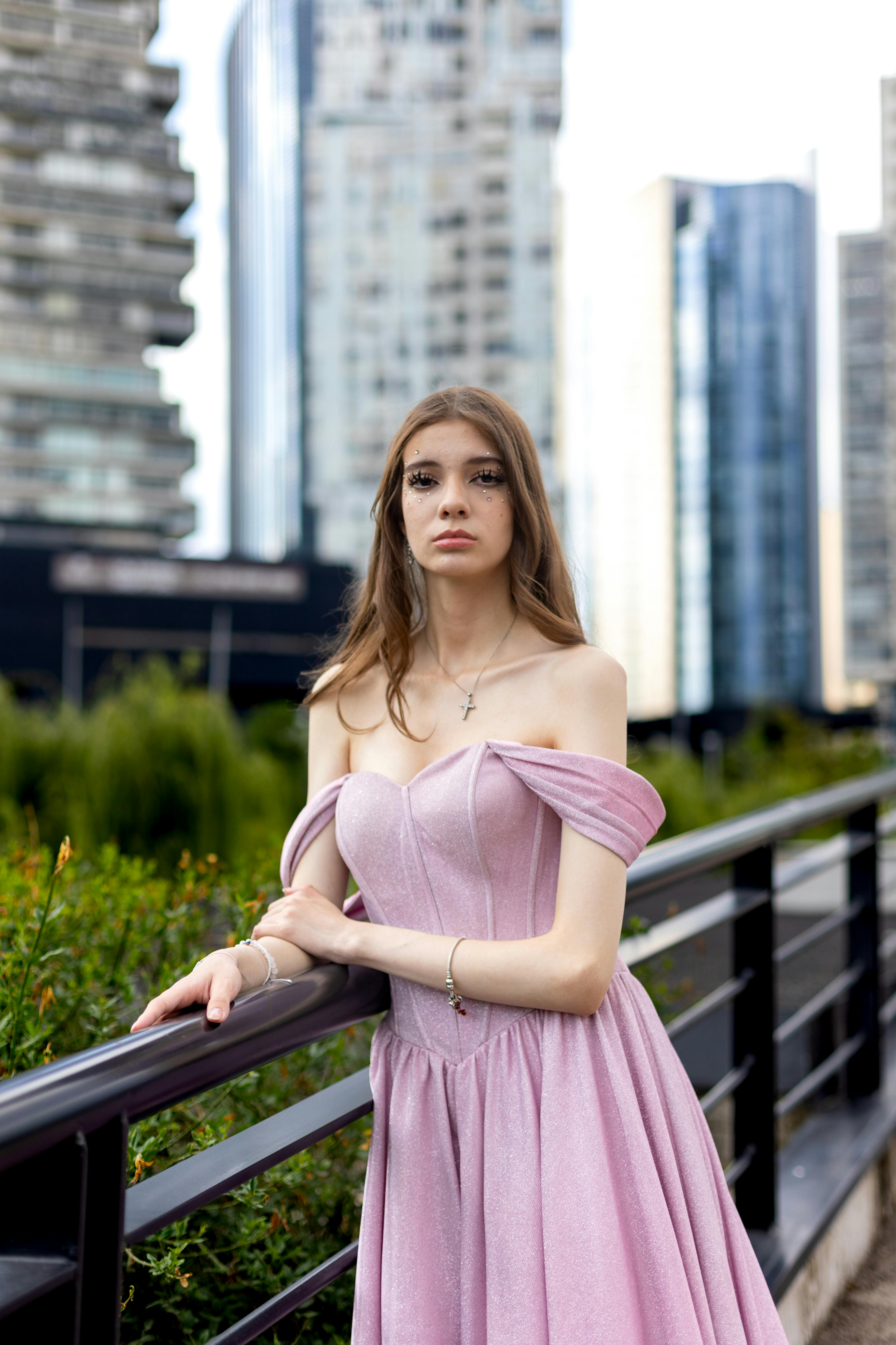 a woman in a pink dress is standing on a bridge