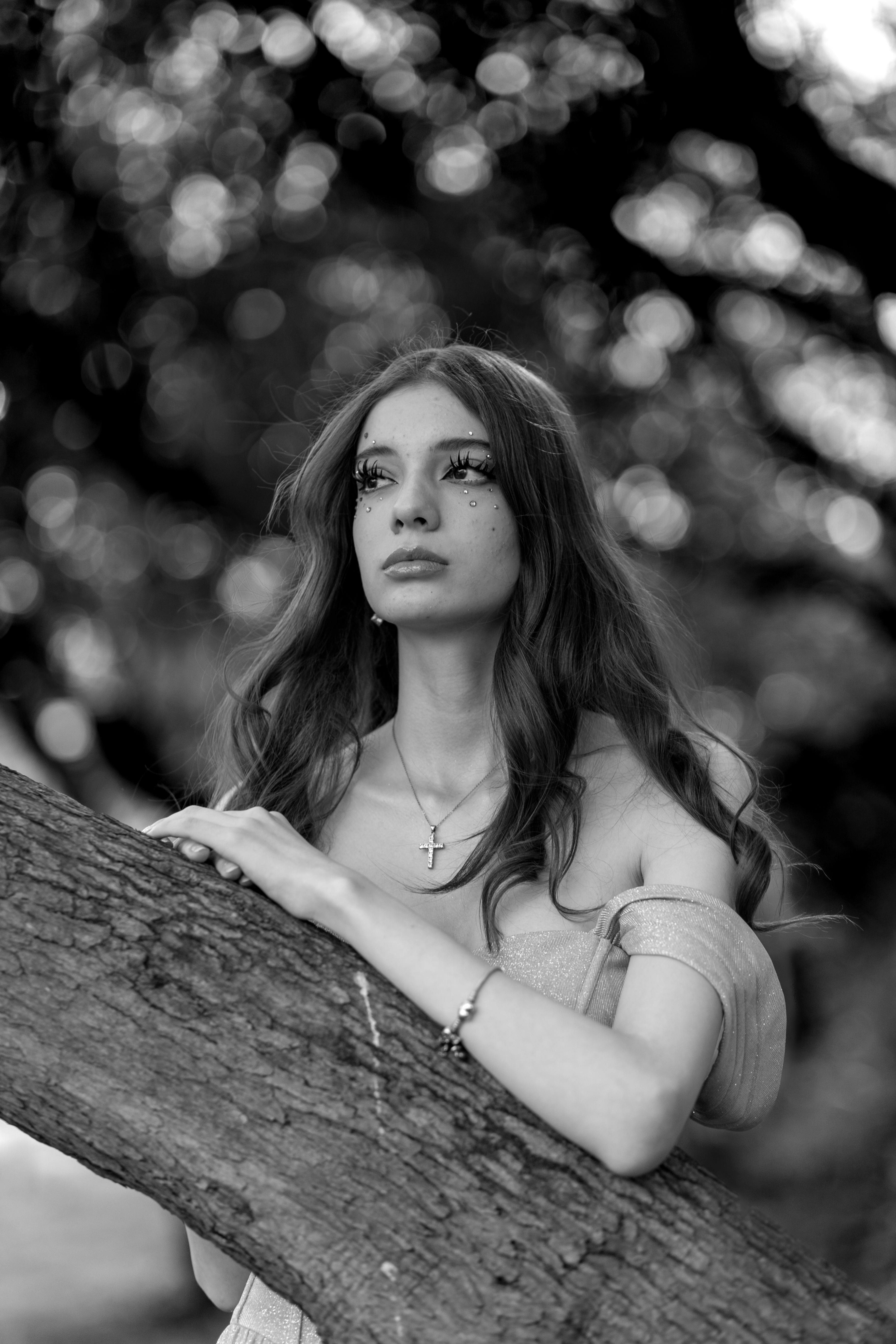 a woman leaning against a tree in black and white