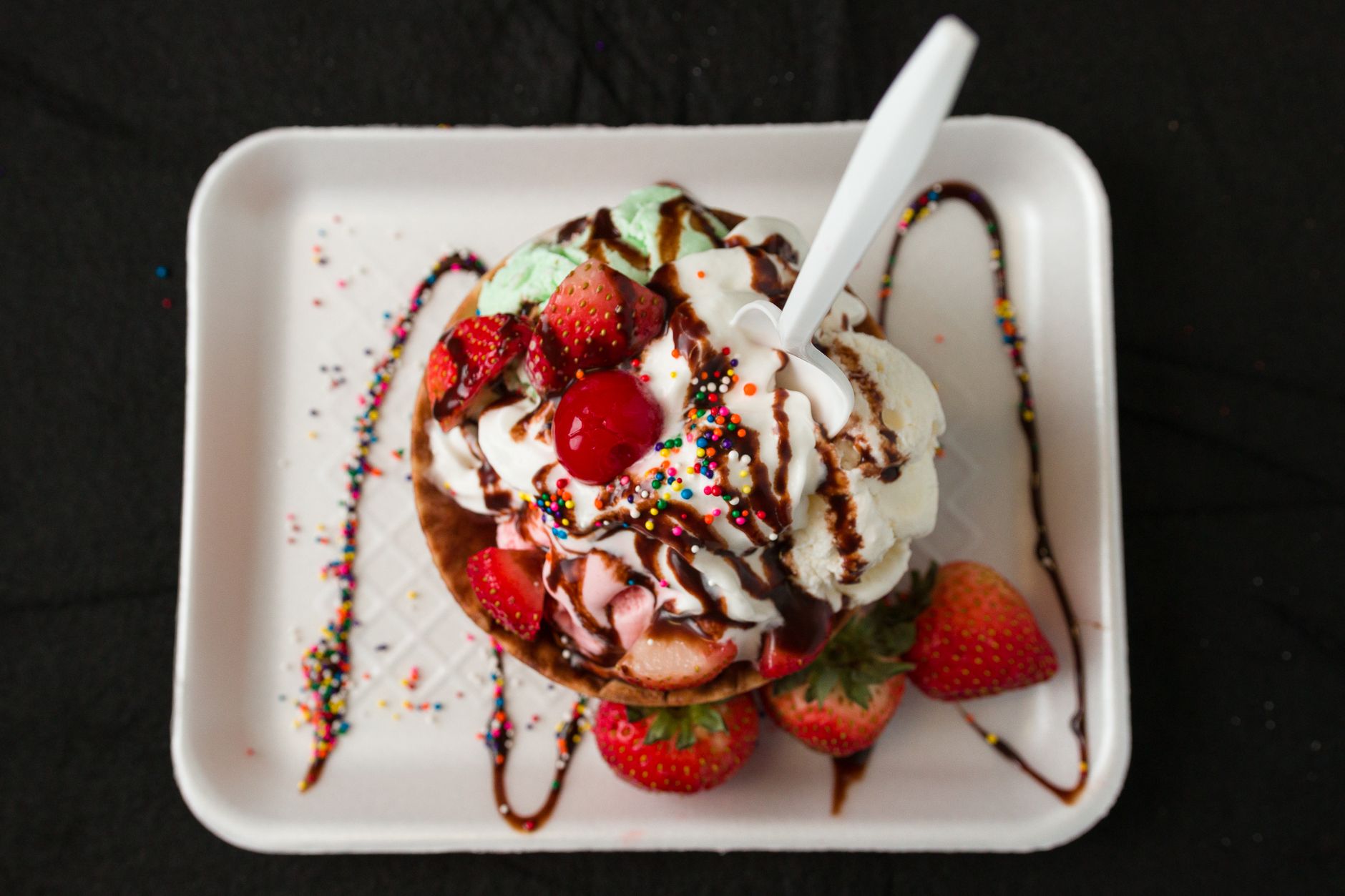 Bright red strawberry sauce drizzled over vanilla ice cream