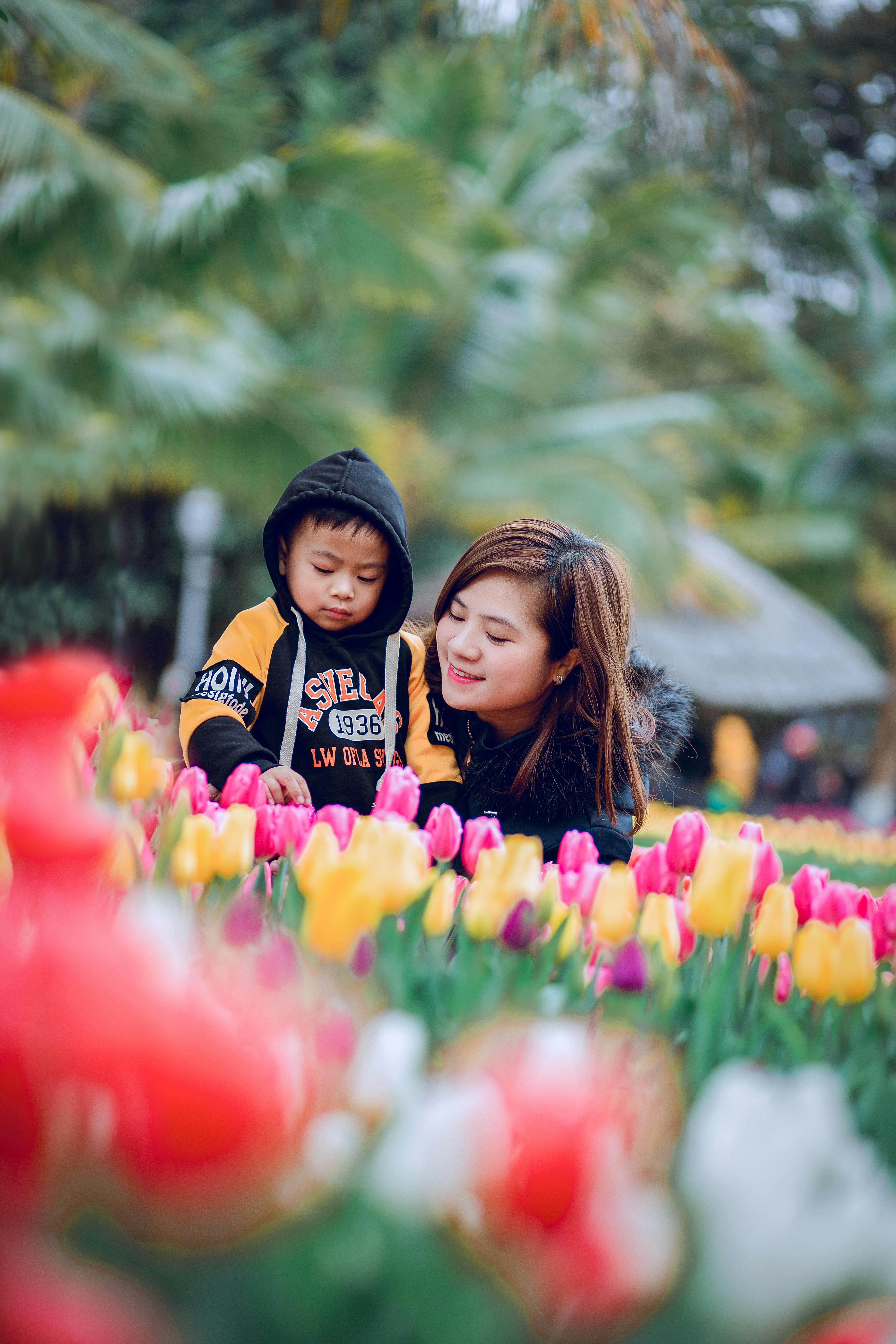 selective focus photography of woman and toddler on flower bed